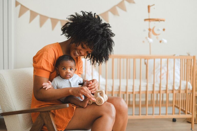 Une mère joyeuse et son bébé profitent d'un moment de jeu dans un nursery confortable, créant un moment familial chaleureux.