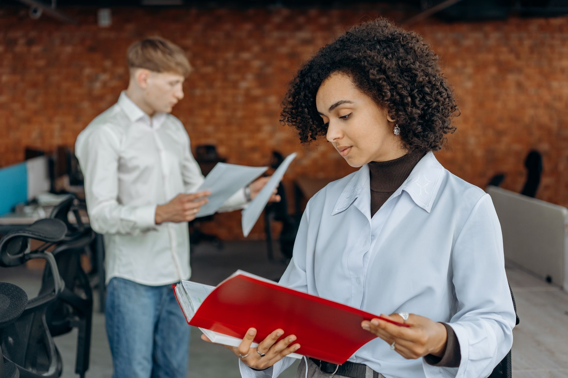 Deux jeunes professionnels collaborent sur des rapports financiers dans un espace de bureau contemporain.