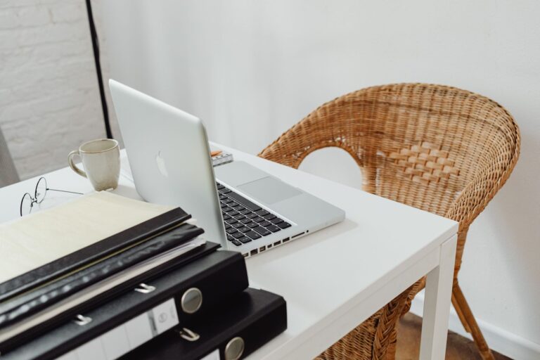 Un bureau à domicile cosy avec un ordinateur portable, des classeurs et une chaise en osier pour un travail à distance productif.