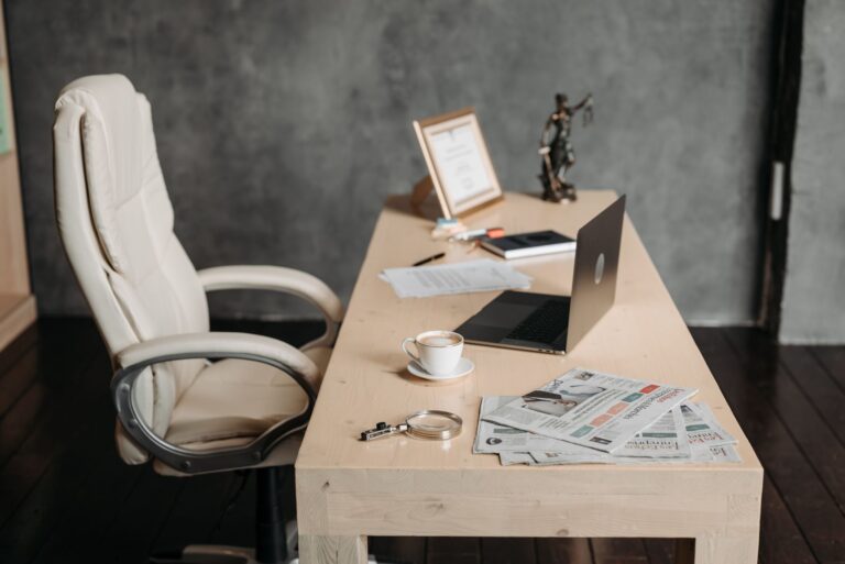 Un espace de travail de bureau propre avec une tasse de café, un ordinateur portable et des journaux sur un bureau en bois pour un environnement productif.