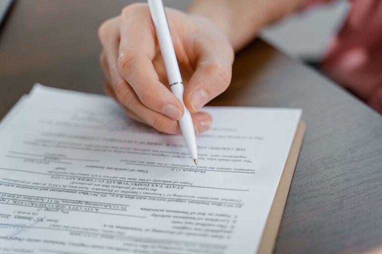 Une main tenant un stylo signant un document, plan rapproché avec mise au point sur le papier.
