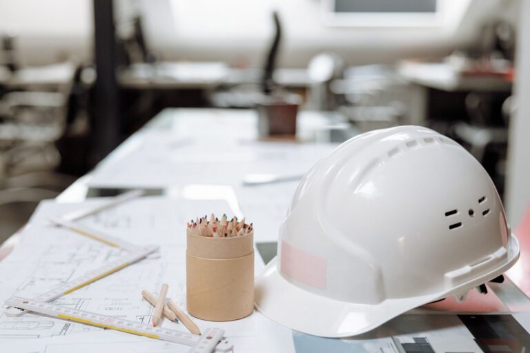 Gros plan d'un bureau avec un casque blanc, des crayons de couleur et des plans architecturaux.