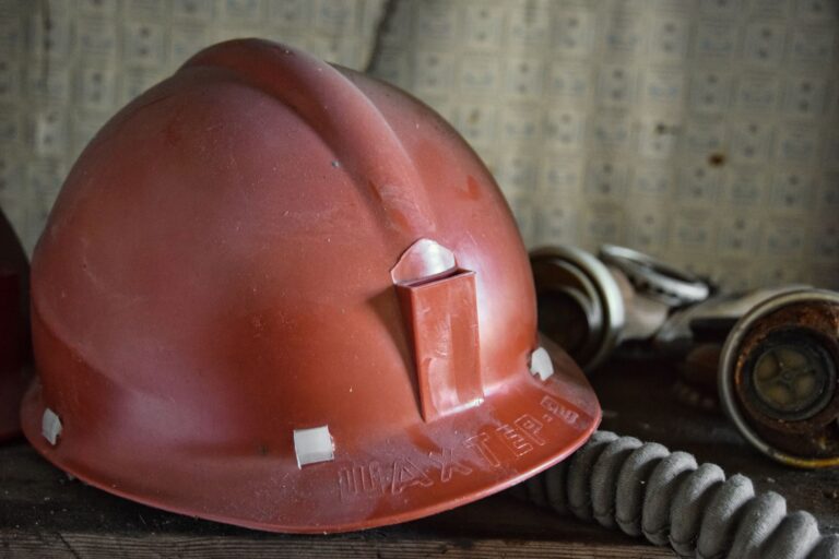 Gros plan d'un casque de sécurité rouge et d'un masque filtrant dans un cadre industriel.