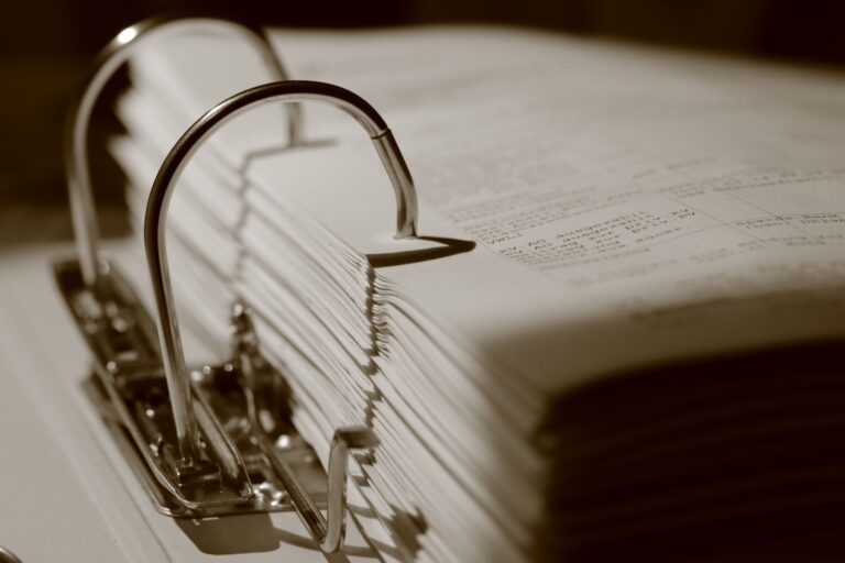 Gros plan détaillé en sépia d'un classeur rempli de documents, mettant l'accent sur la texture.