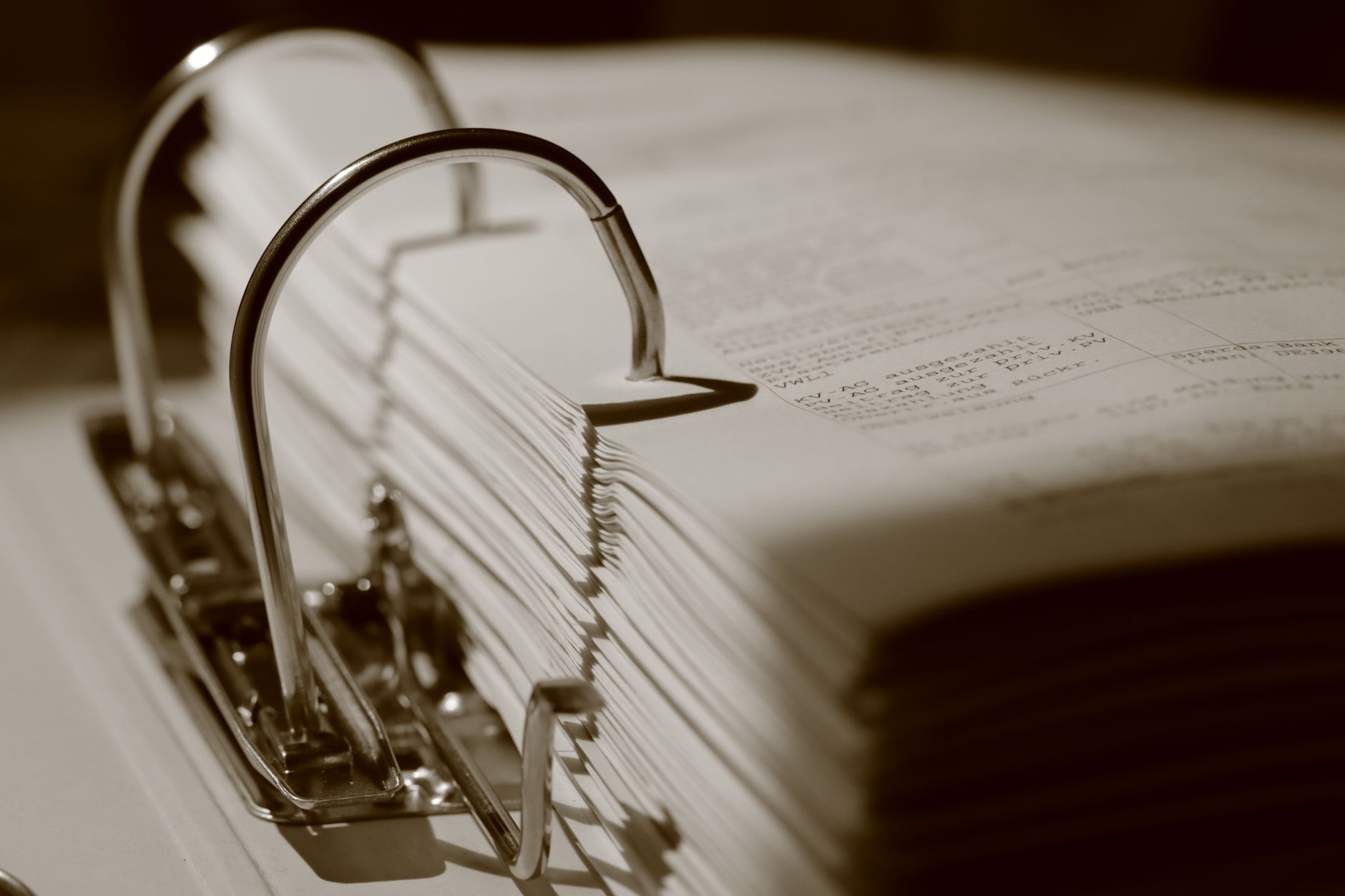 Gros plan détaillé en sépia d'un classeur rempli de documents, mettant l'accent sur la texture.