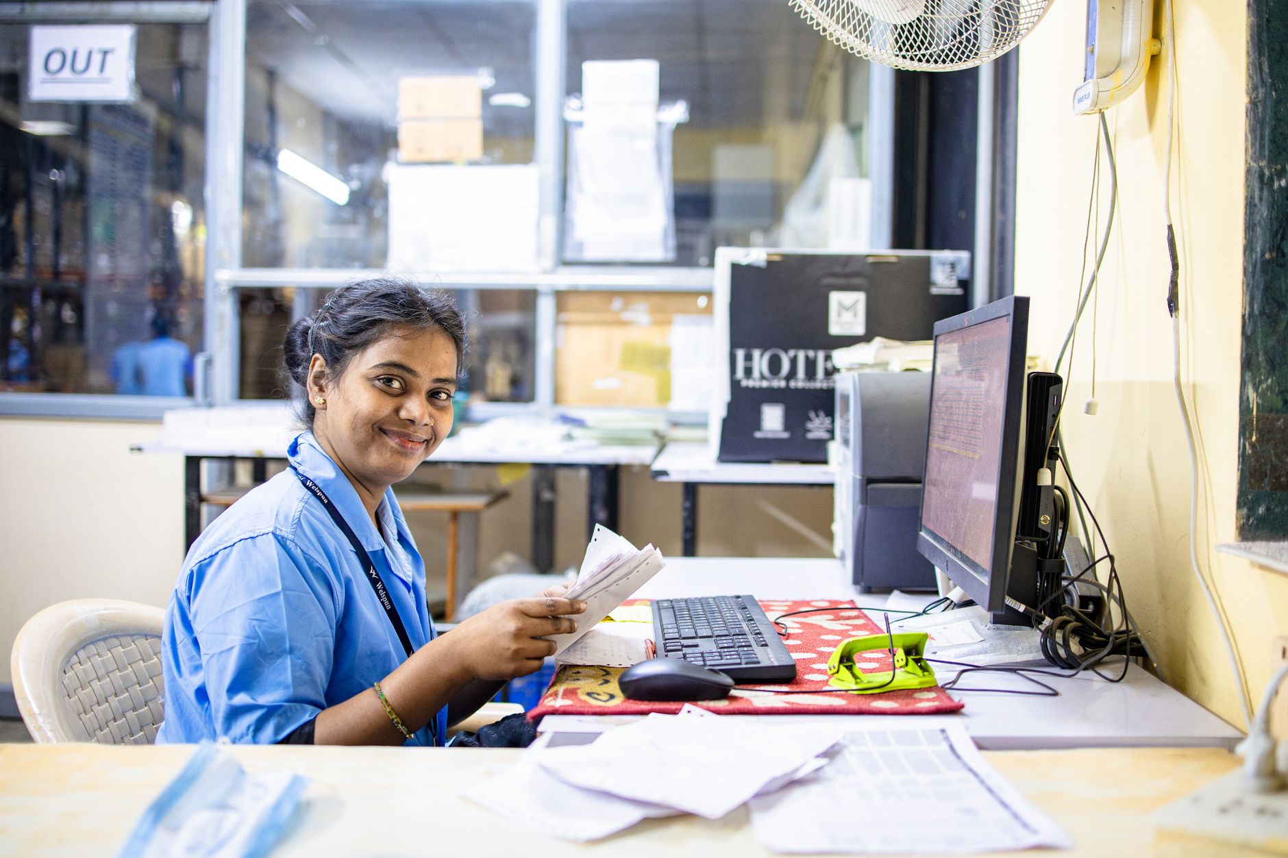 Employée de bureau souriante dans un espace de travail moderne, manipulant des documents à son bureau.